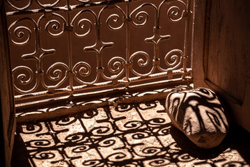 Shadow of an typical ornate window grid falling onto a stone, a kasbah at the Road of the Kasbahs in Morocco