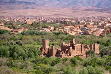 Fototapeta na wymiar Old deserted big Kasbah on a hill surrounded by a palm grove in the valley of roses