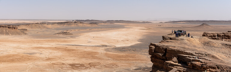 Tourists enjoying the scenic view of the Sahara desert from mount Gara Medouar - obrazy, fototapety, plakaty