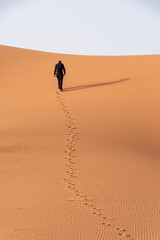 A person walking through the Erg Chebbi desert in the African Sahara