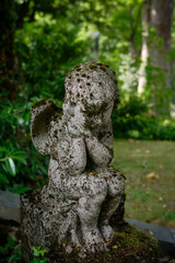 small tired mossy putto sitting on a grave