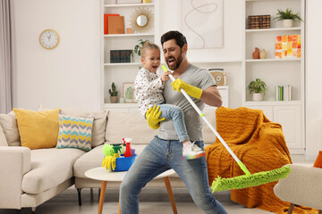 Spring cleaning. Father and daughter singing while tidying up together at home - obrazy, fototapety, plakaty