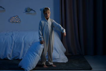 Boy in pajamas sleepwalking indoors at night