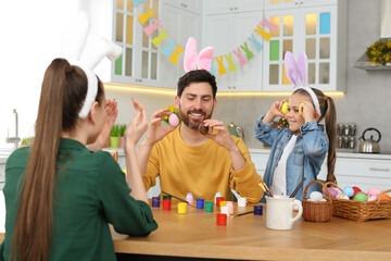 Family having fun while painting Easter eggs at table in kitchen