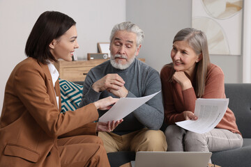 Insurance agent consulting elderly couple about pension plan in room