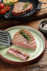 Delicious tuna steak with rosemary served on wooden table