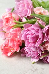 Fototapeta na wymiar Beautiful bouquet of colorful tulip flowers on light table, closeup