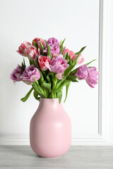 Beautiful bouquet of colorful tulip flowers on floor near white wall