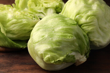 Fresh green whole and cut iceberg lettuce heads on wooden table, closeup