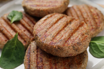 Tasty grilled vegan cutlets and spinach on plate, closeup