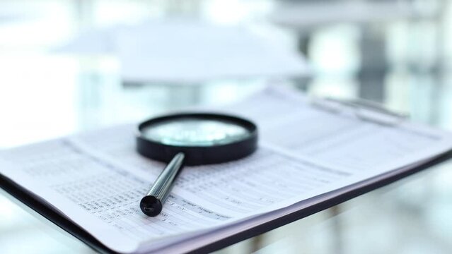 glass pointing at numbers on financial documents. Concept of finance, search and accounting.
