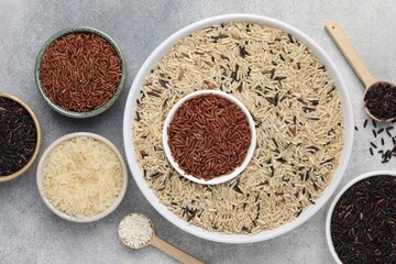 Different sorts of rice on grey table, flat lay