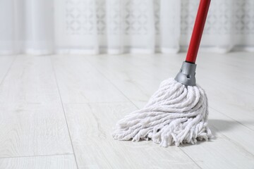 Cleaning dirty parquet floor with mop indoors. Space for text