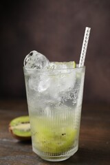 Glass of refreshing drink and cut kiwi on wooden table, closeup