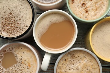 Many cups with different aromatic coffee on wooden table, flat lay