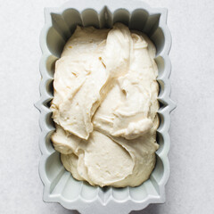 Lemon cake batter in a loaf pan, cake batter about to be baked in a silver baking pan, the process of making lemon pound cake