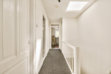 a long hallway with white walls and carpeting on the floor, leading to an open door that leads to another room
