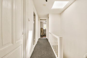 a long hallway with white walls and carpeting on the floor, leading to an open door that leads to...