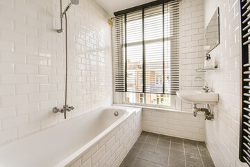 a white bathroom with black and white tiles on the floor, tub, shower, and window in the background