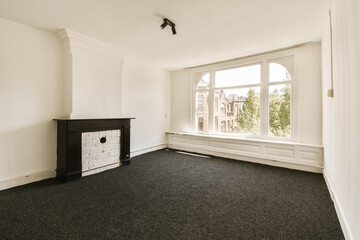 an empty room with a fire place in the corner and black carpeting on the floor next to the window