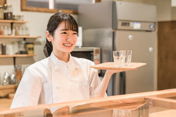 飲食店の厨房で水を持つ調理師のアジア人女性
