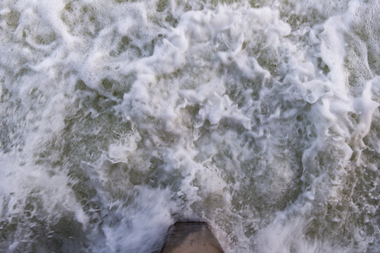 Water rushes past a concrete pylon