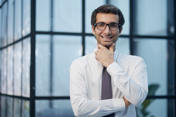 Thinking about business. Thoughtful young man in formalwear looking at camera while holding hand on chin