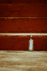 Square empty bottle by the concrete red stairs