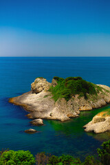 Naklejka premium Green rocky island in sea on summer sunny day