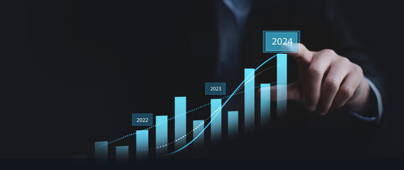 Businessman touching on business growth graph for year 2023 to 2024. new business goals, plans and...