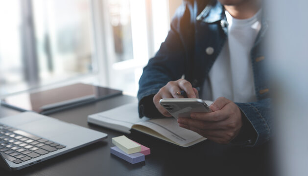 Business Woman Hand Using Mobile Phone, Typing On Smartphone Screen During Planning Work With Calendar Planner And Laptop Computer On Office Table, Close Up