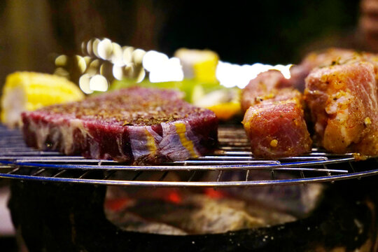 Closed up photo of marinated beef steak and pork ribs on coal grill stove