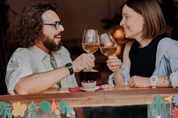 Smiling couple drinking wine at restaurant and talking. Love, dating and holidays concept