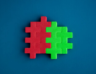 Red and green puzzle blocks are perfectly put together on blue background, minimal style. Business partnership, teamwork, collaboration, and contrast opposite colors concepts.