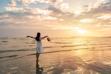 Foto op Aluminium Young woman traveler relaxing and enjoying the beautiful sunset on the tranquil beach, Travel on the summer vacation concept © Kittiphan