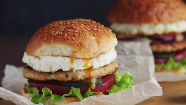 dripping yolk  chicken burger with fried egg  tomato lettuce sauce close up