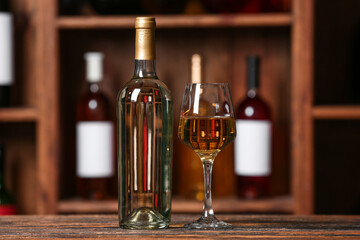 Bottle and glass of exquisite wine on table in cellar