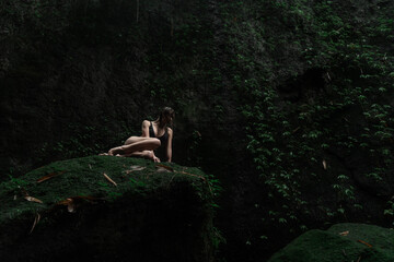 girl in a sexy bikini near a waterfall in the tropical jungle