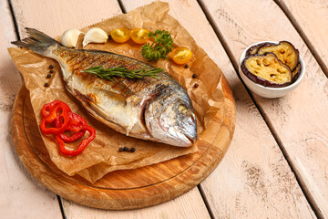 Board with tasty grilled dorado fish on light wooden background