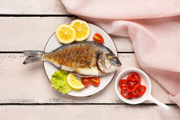 Plate with tasty grilled dorado fish on light wooden background