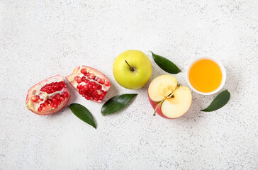 Composition with ripe apples, pomegranate, plant leaves and honey on light background. Rosh hashanah (Jewish New Year) celebration