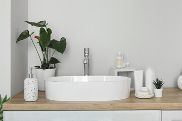 Fototapeta na wymiar Sink bowl and bath accessories on wooden counter in bathroom
