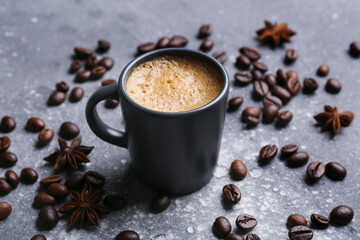 Cup of hot espresso and coffee beans on grey background