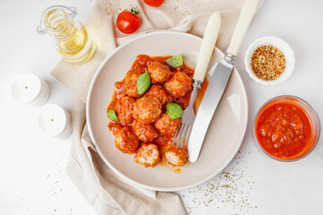 Plate of tasty meat balls with tomato sauce and basil on white background