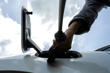 Progressive concept of electric rechargeable car, hand inserting charger device from electric...
