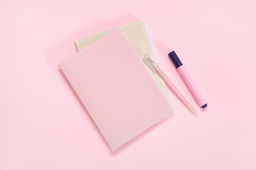 Notebook with pen and marker on pink background