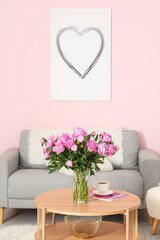 Vase of pink peonies on coffee table with couch in living room