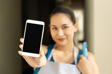 Modern Connectivity, Young happy smiling Asian Woman, Low-Paid Cleaner Worker, Holding Blank Smartphone, Embracing Technology in Urban Life
