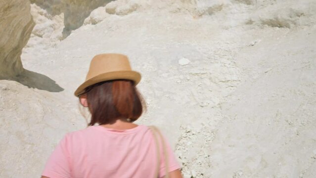 Young woman walking among the stones with hat ans sunglasses. 4k video footage UHD 3840x2160