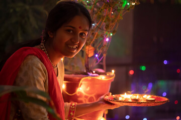 Indian girl placing diya with smiling at home on 